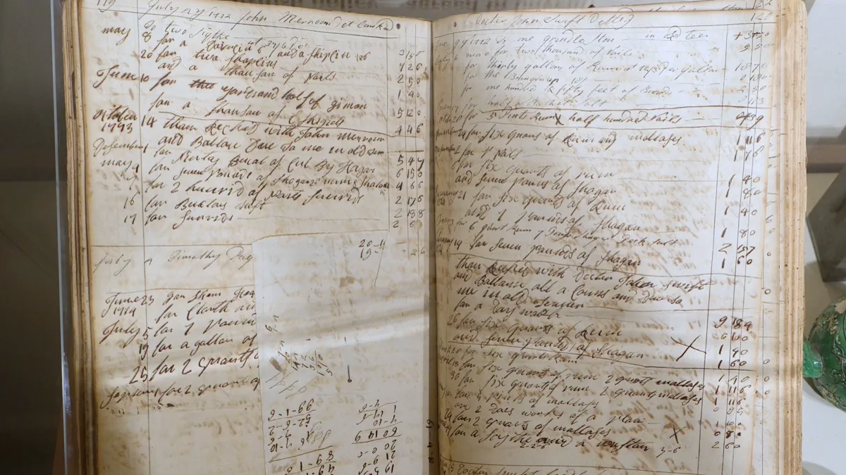 An open account book with columns of handwritten entries in brown ink, ruled lines, dates down the left of each page and sums at the foot.