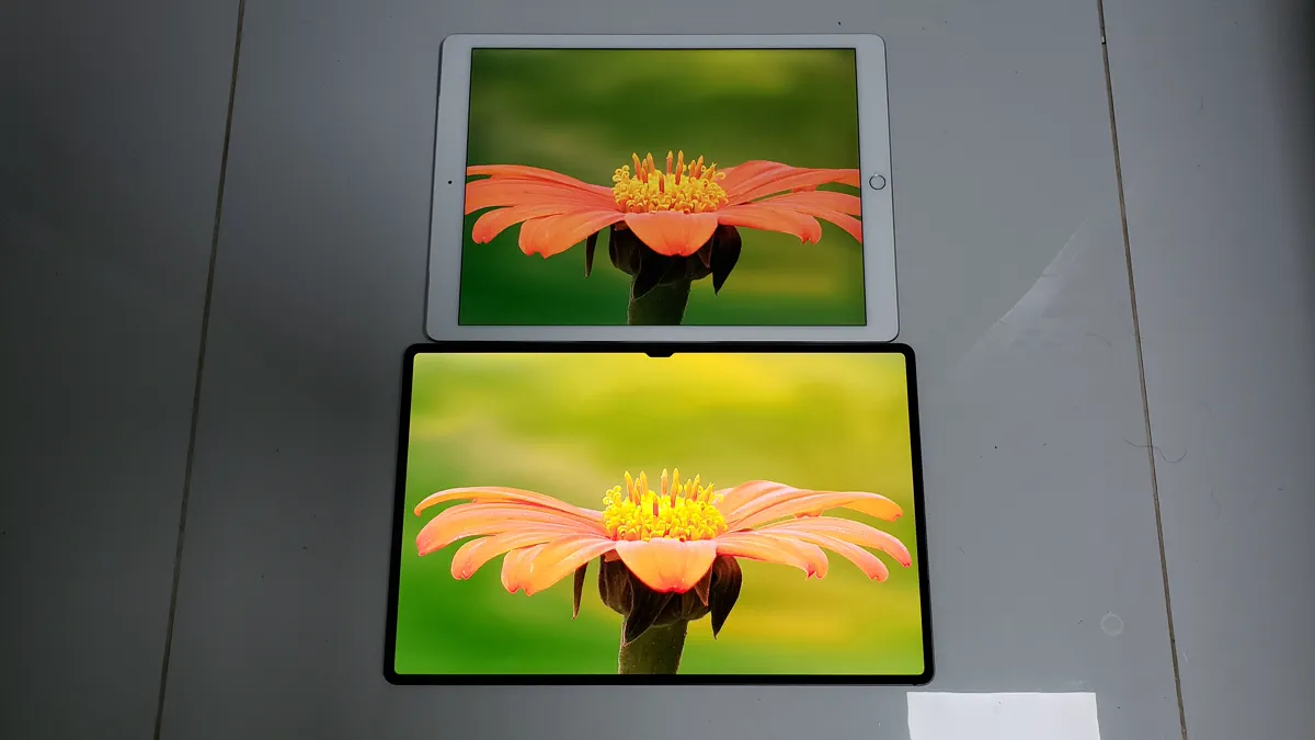 Two tablet computers lying on a table, both showing the same photograph of an orange flower, the upper one in a squarer shape and the lower one in a longer, wider shape.